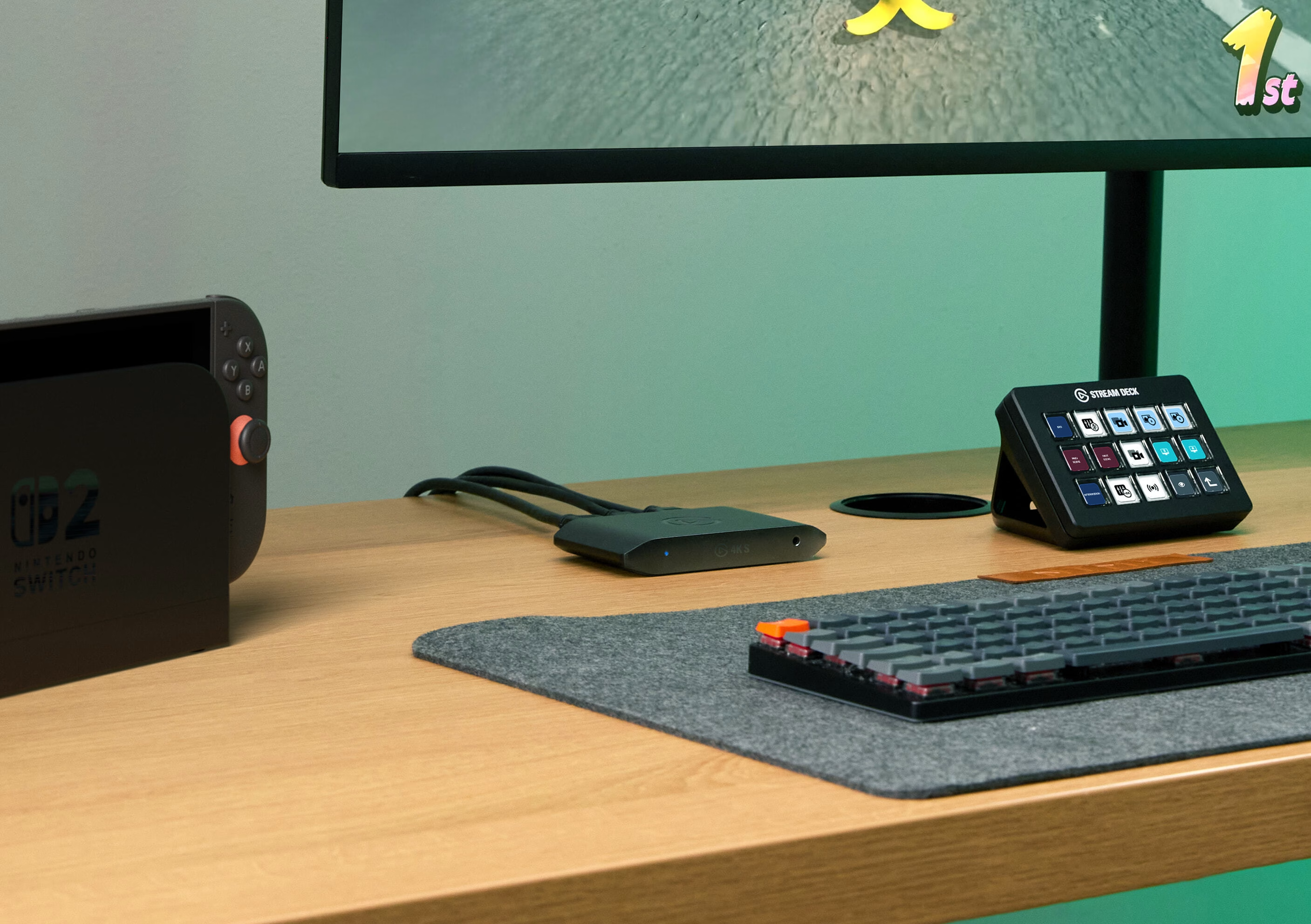 Schreibtisch-Setup mit Nintendo Switch, Monitor, Stream Deck, Tastatur und Kabelbox. Ein Spiel ist auf dem Monitor.