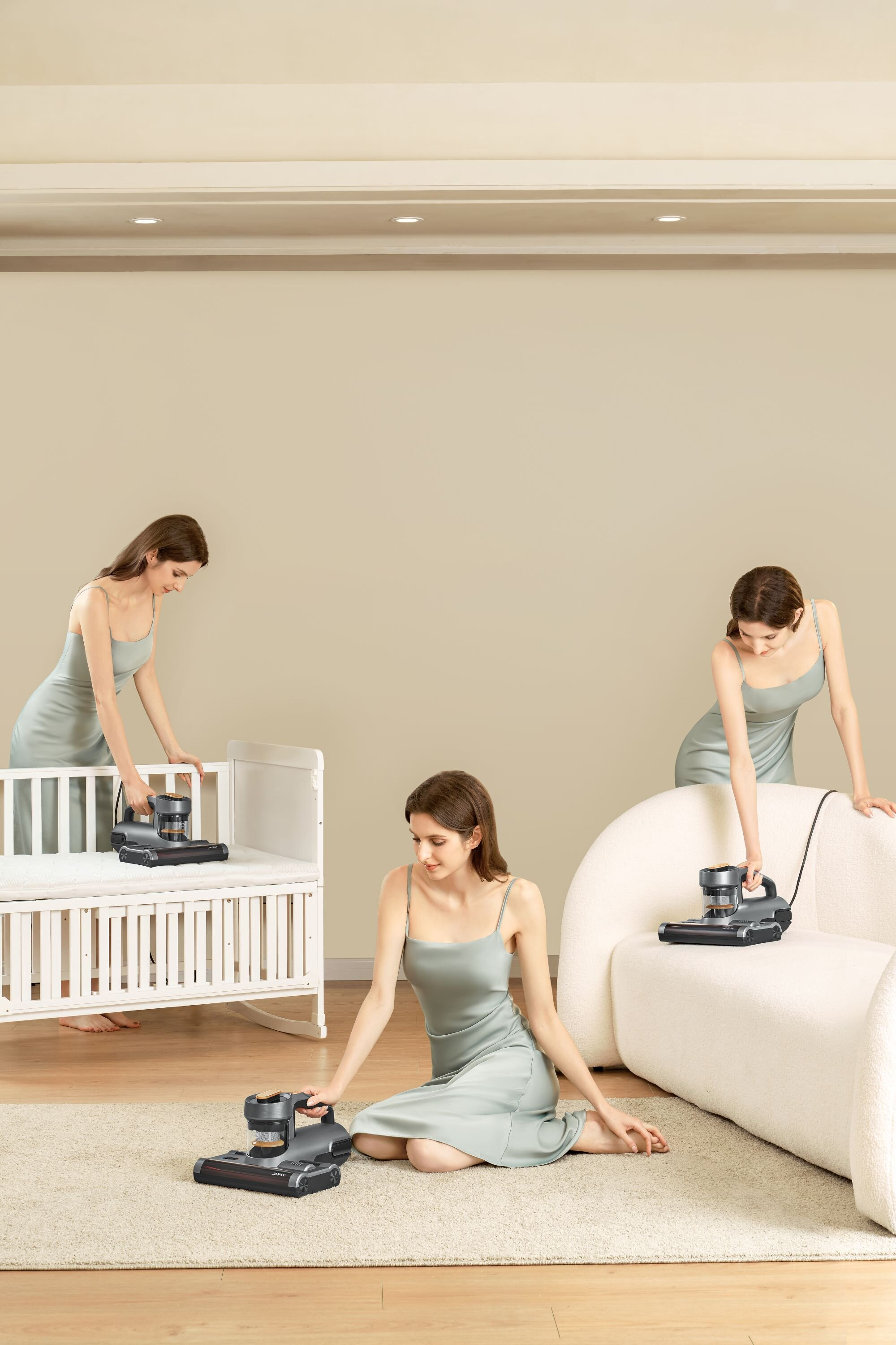 Kobieta używa odkurzacza na dywanie, łóżeczku i sofie. Tło to beżowa ściana.