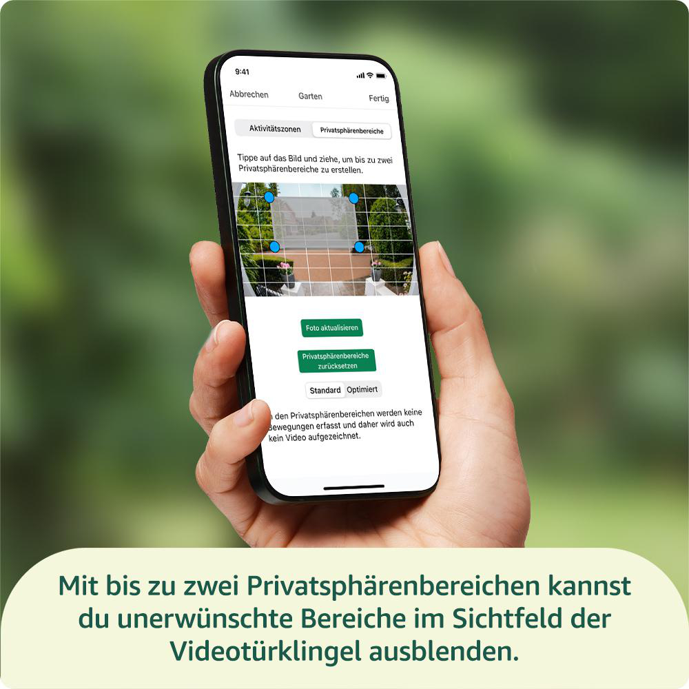 Eine Hand hält ein Telefon, das eine Oberfläche zum Einstellen von Privatzonen auf einer Kamera anzeigt. Der Hintergrund ist ein verschwommener Garten.