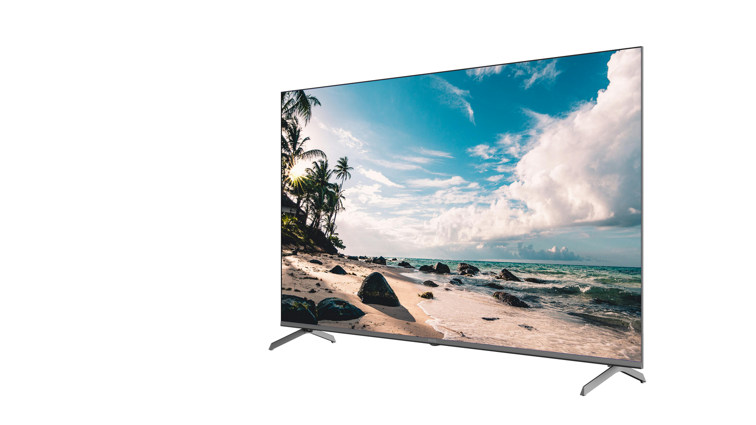 Televisor que muestra una escena de playa: arena, rocas, palmeras, cielo azul y nubes. El televisor está sobre un fondo blanco.