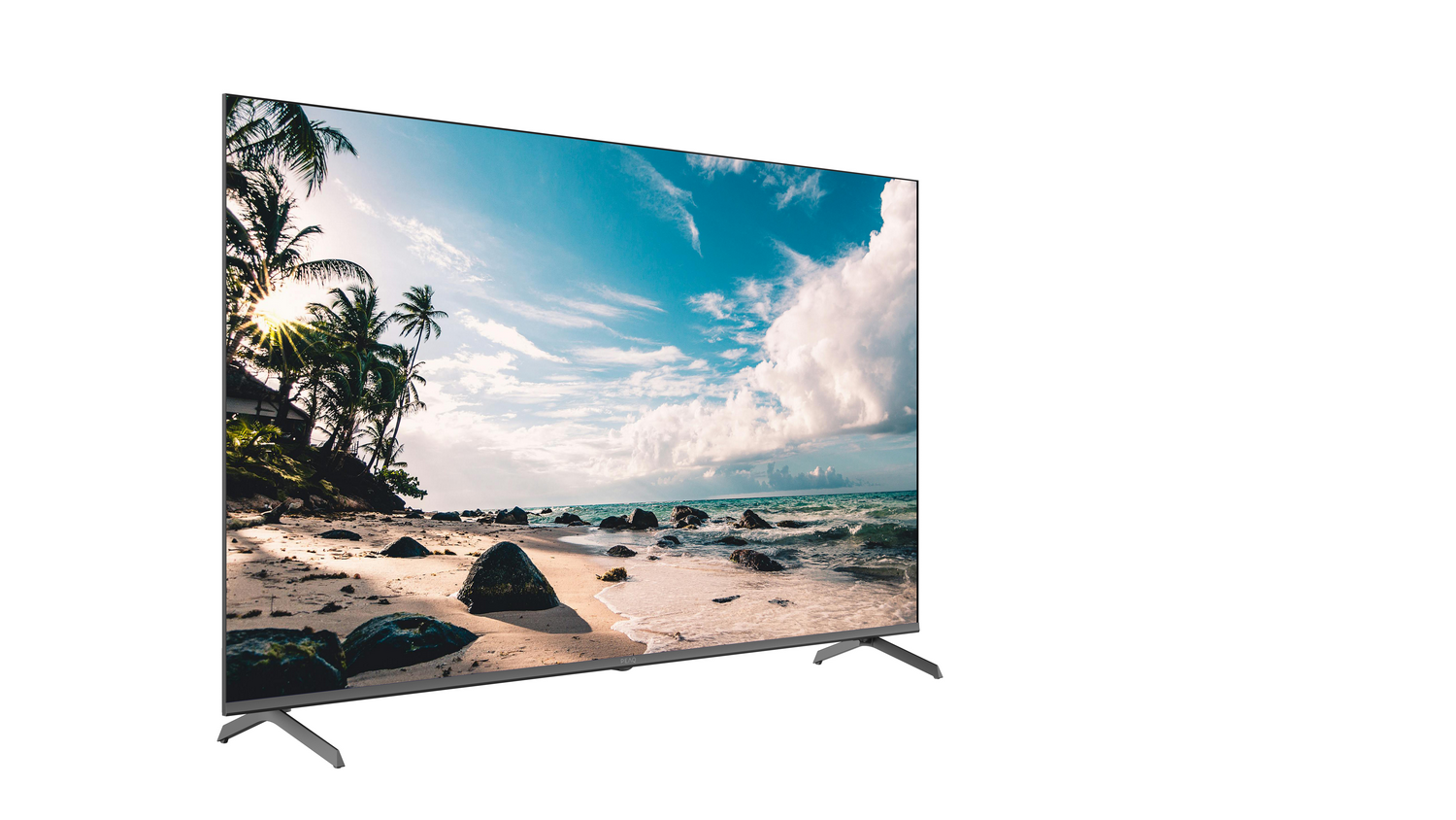 Un televisor muestra una escena de playa con palmeras, arena, rocas y océano bajo un cielo brillante con nubes.