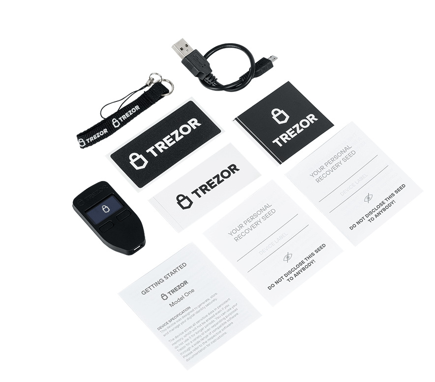 Czarny portfel sprzętowy Trezor z akcesoriami: kabel USB, smycz, karty. Białe tło.