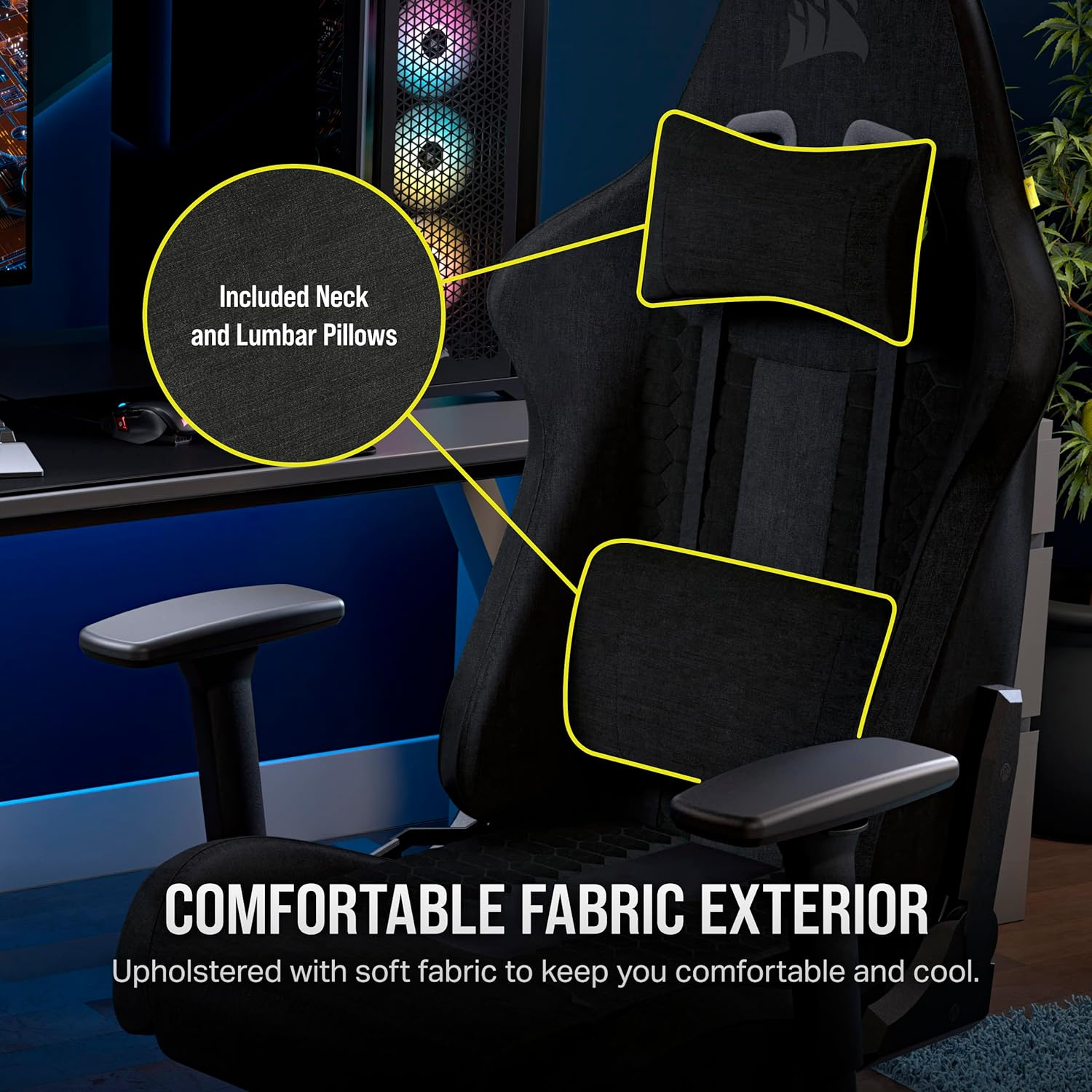 Black gaming chair with neck and lumbar pillows. Features a comfortable fabric exterior for user comfort. Background shows a PC and plant.
