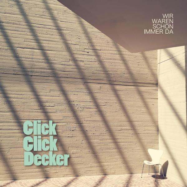 Eine Betonmauer mit den Worten 'Click Click Decker'. Schatten und ein weißer Stuhl sind sichtbar. Text auf Deutsch: 'Wir waren schon immer da.'