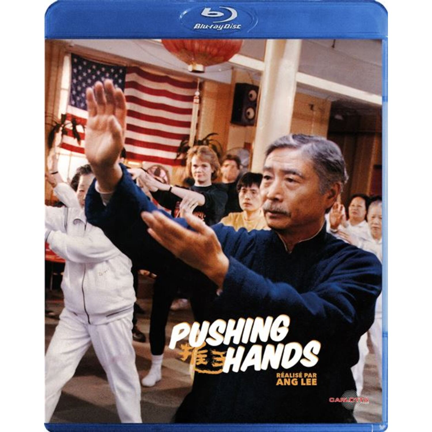 Boîtier Blu-ray pour Pushing Hands. Un homme âgé en chemise bleue dirige un groupe de personnes dans une pose d'arts martiaux.