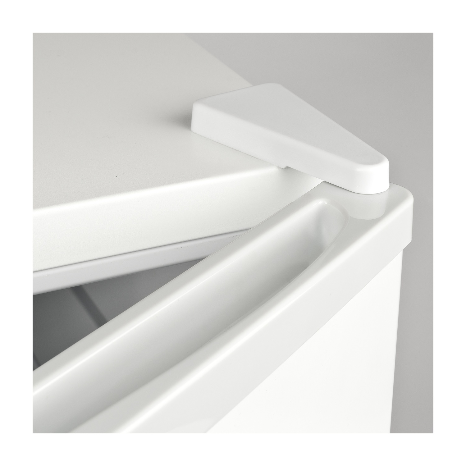 Primo piano di un angolo di mobile bianco. Un pezzo triangolare è in cima, con una scanalatura curva sotto. Linee pulite e illuminazione brillante.