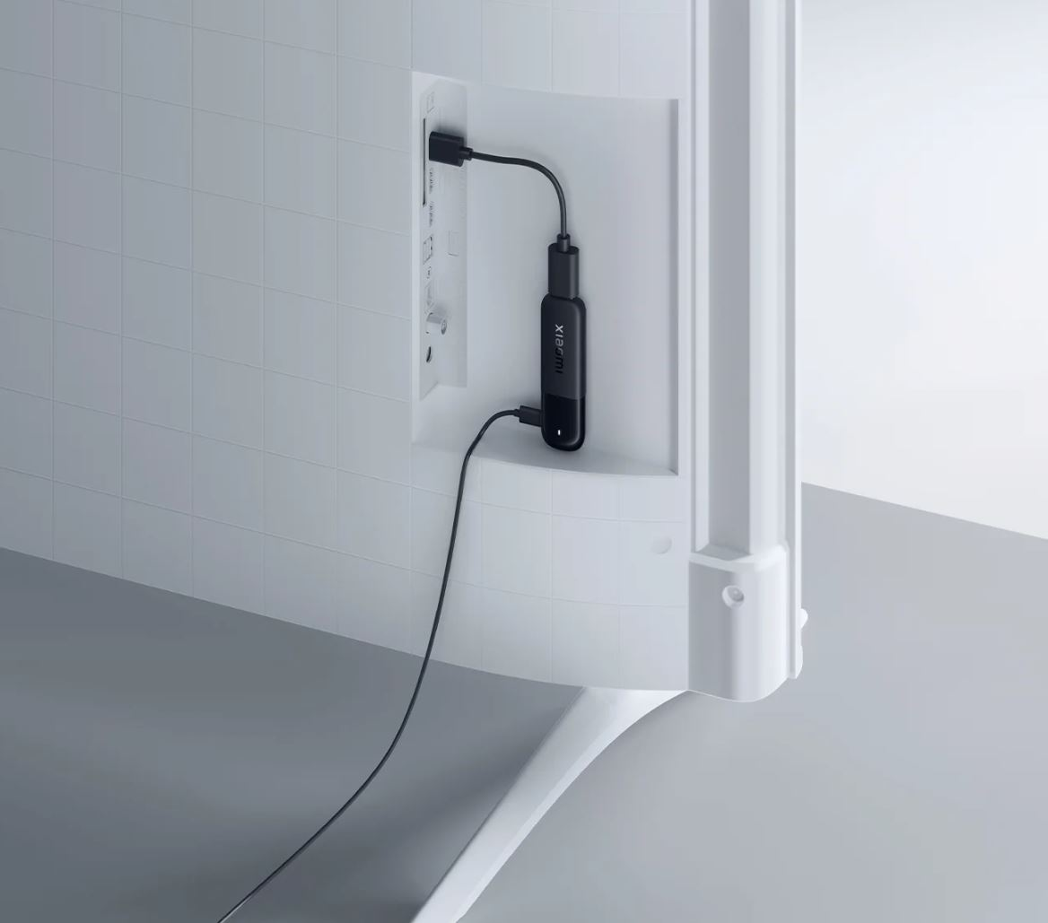 Czarne urządzenie do strumieniowania Xiaomi jest podłączone do tyłu białego telewizora. Kable są podłączone do telewizora i urządzenia.