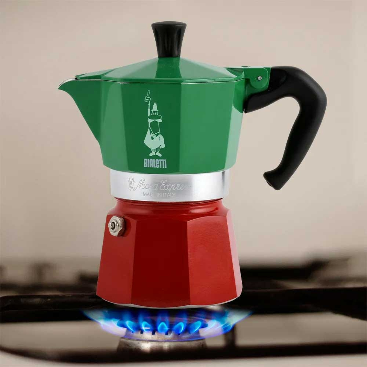 Una caffettiera Bialetti Moka Express rossa e verde è appoggiata su un fornello a gas con fiamme blu. Il manico è nero.