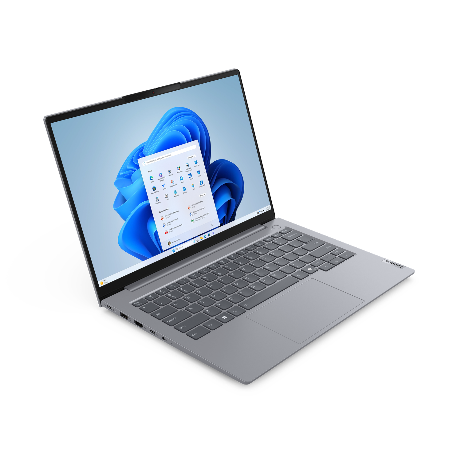 A silver Lenovo laptop is open, displaying the Windows 11 start menu. The background is black. The keyboard and screen are visible.