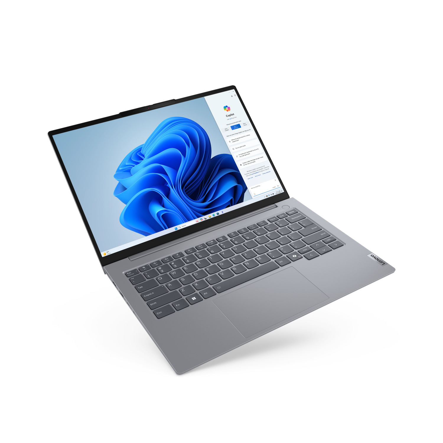 A silver Lenovo laptop is open, displaying a Windows interface with a blue wavy background and a Copilot window.