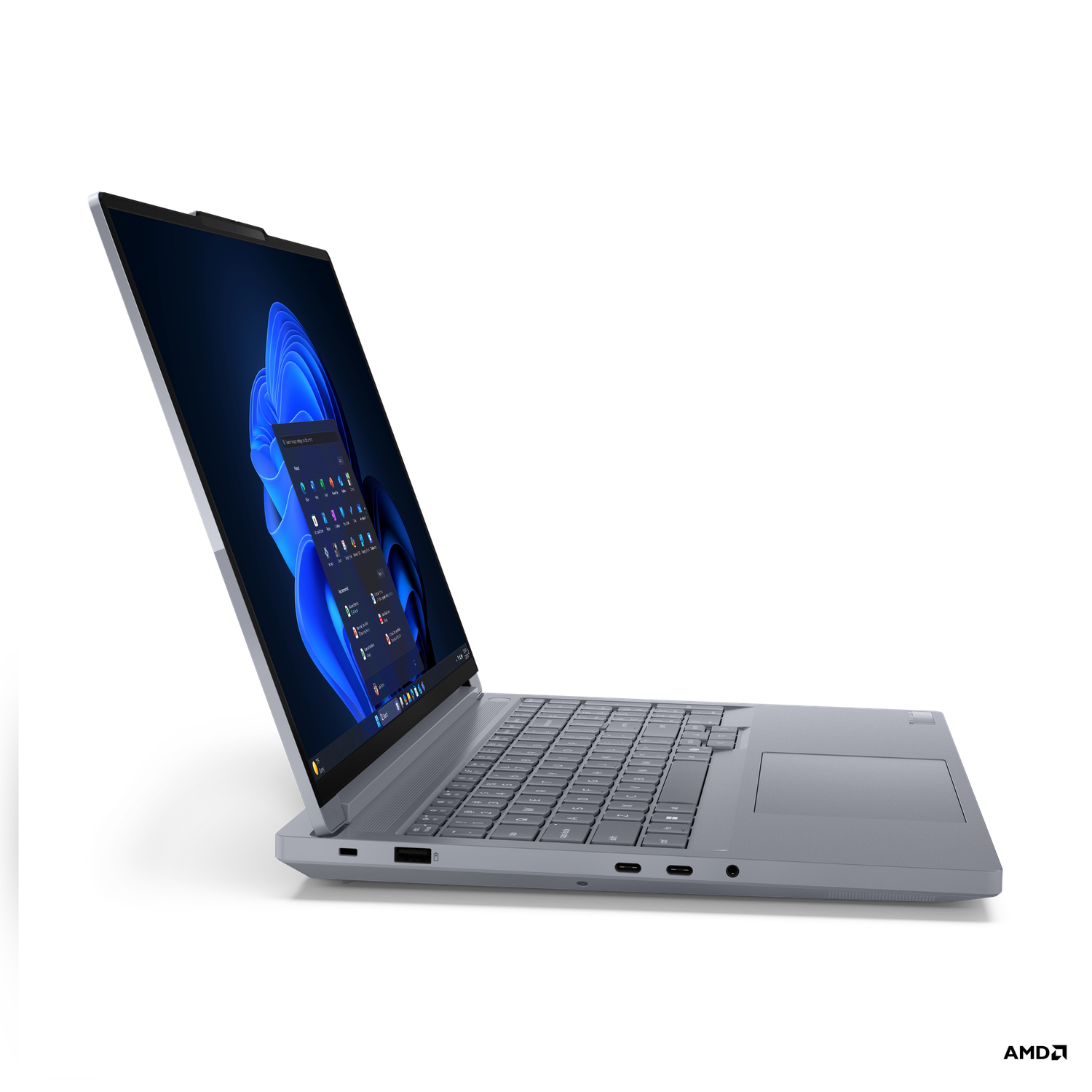 A gray laptop is open, displaying a Windows desktop on a black background. The screen shows blue waves and icons.