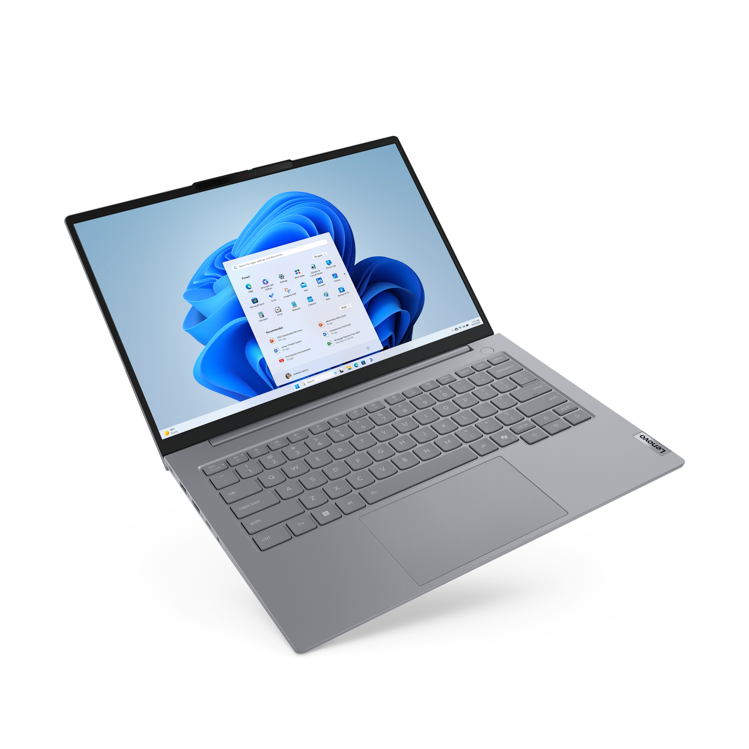 A grey Lenovo laptop is open, displaying the Windows 11 interface. The screen shows app icons. The keyboard is visible, with the Lenovo logo.