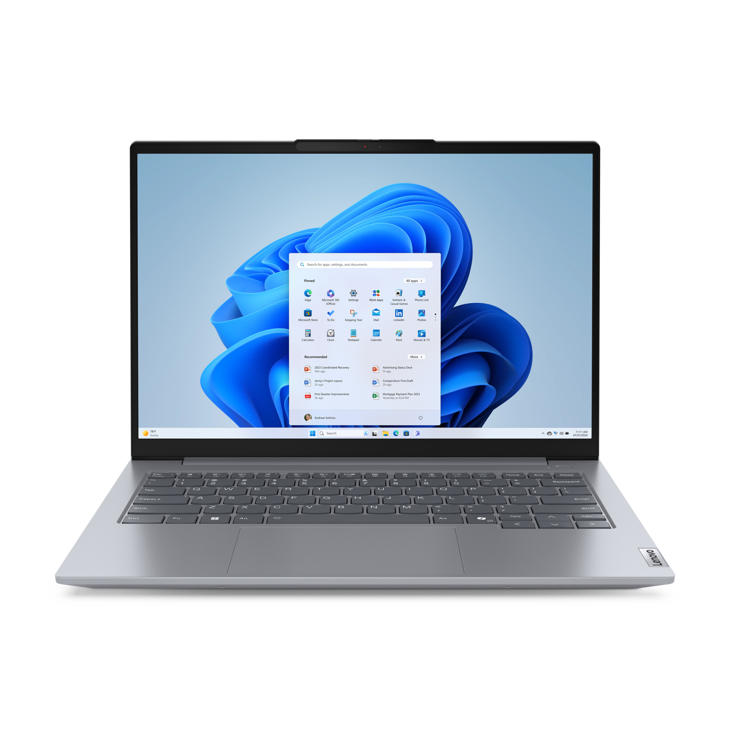 Zilveren laptop op zwarte achtergrond, Windows 11-scherm zichtbaar. Toetsenbord, touchpad en Lenovo-logo aanwezig. Het scherm toont app-pictogrammen.