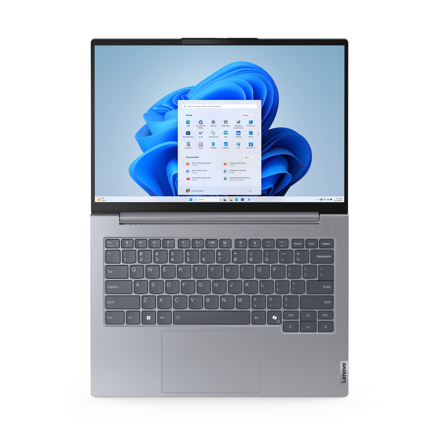 Een zilveren Lenovo laptop toont de Windows 11 interface, met een blauwe achtergrond en diverse app-iconen. Het toetsenbord is zichtbaar.