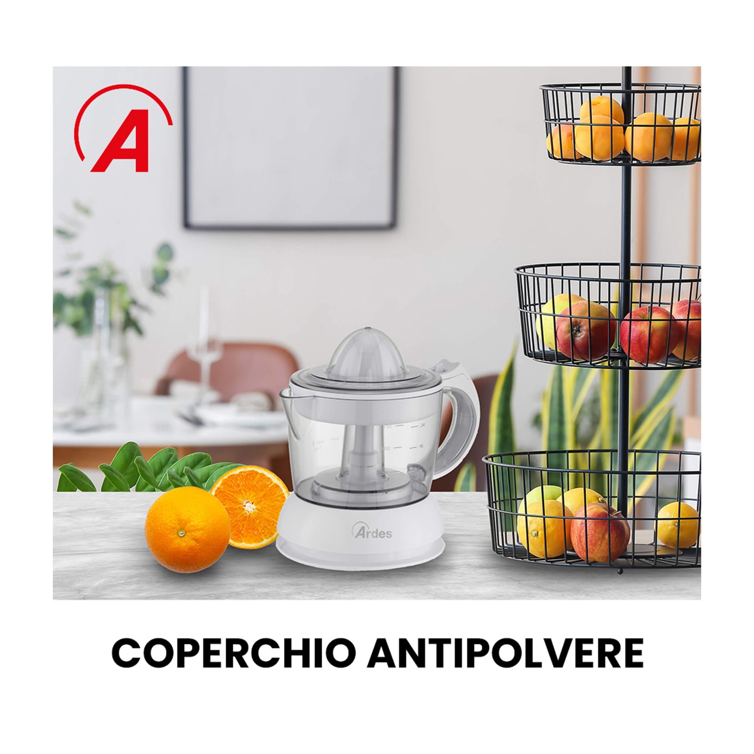 Uno spremiagrumi bianco con coperchio trasparente è su un tavolo, arance accanto. Un portafrutta contiene arance, mele e limoni.