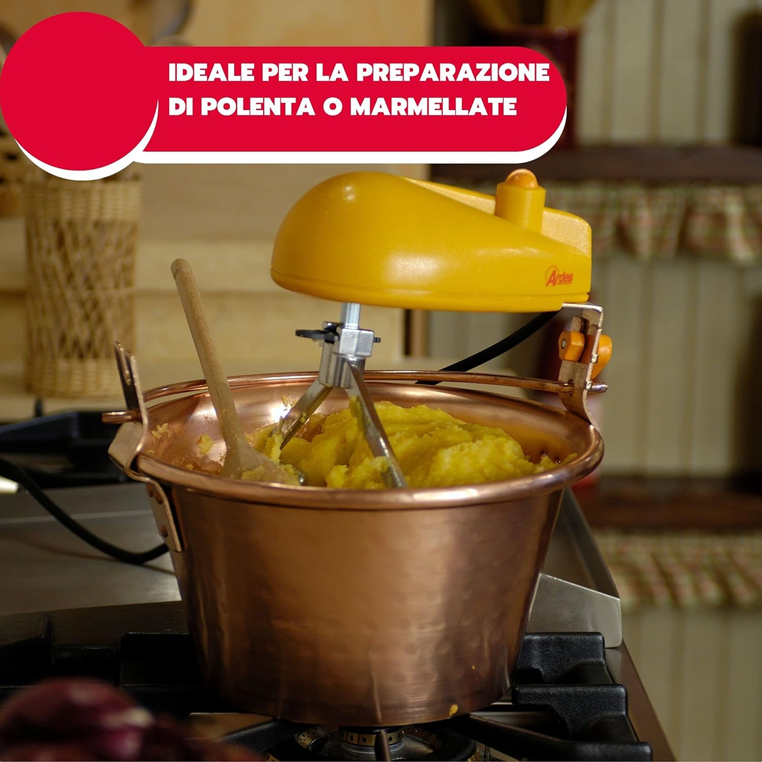 Macchina gialla per polenta che mescola polenta gialla in un recipiente di rame. Il recipiente è su un fornello. Il testo sopra dice: 'Ideale per polenta o marmellata'.