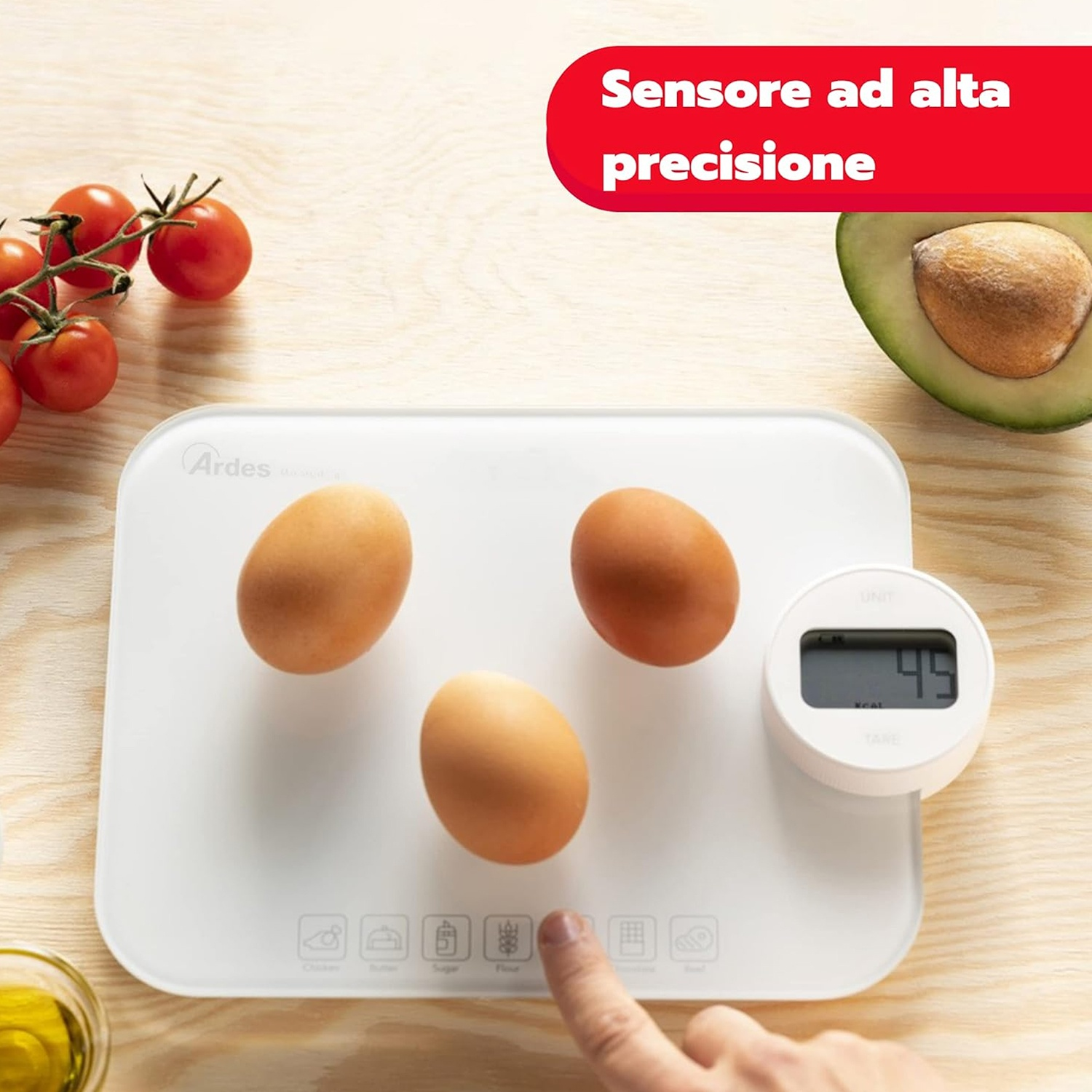 Una bilancia da cucina con uova, avocado e pomodori. Una mano tocca un pulsante. La bilancia indica 45. Un banner rosso dice 'Sensore ad alta precisione'.