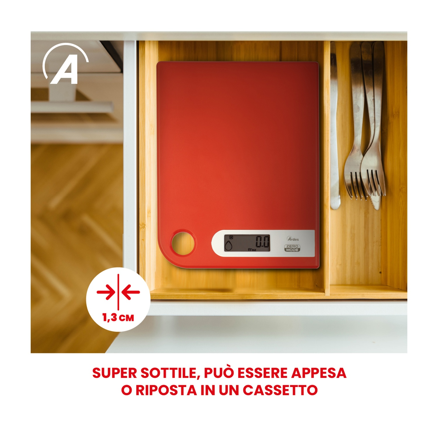 Una bilancia da cucina rossa si trova in un cassetto con forchette e un coltello. È etichettata come 'Ardes'. Il cassetto è in un mobile bianco.