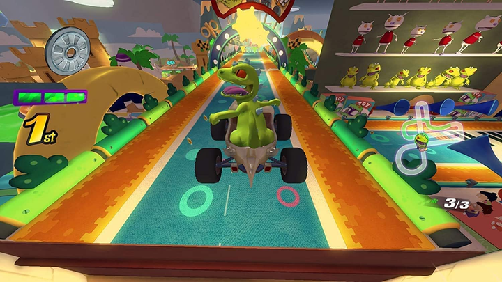 Un dinosaurio verde en un kart corre en una pista colorida. La pista está bordeada de juguetes e instrumentos musicales. El dinosaurio está en primer lugar.