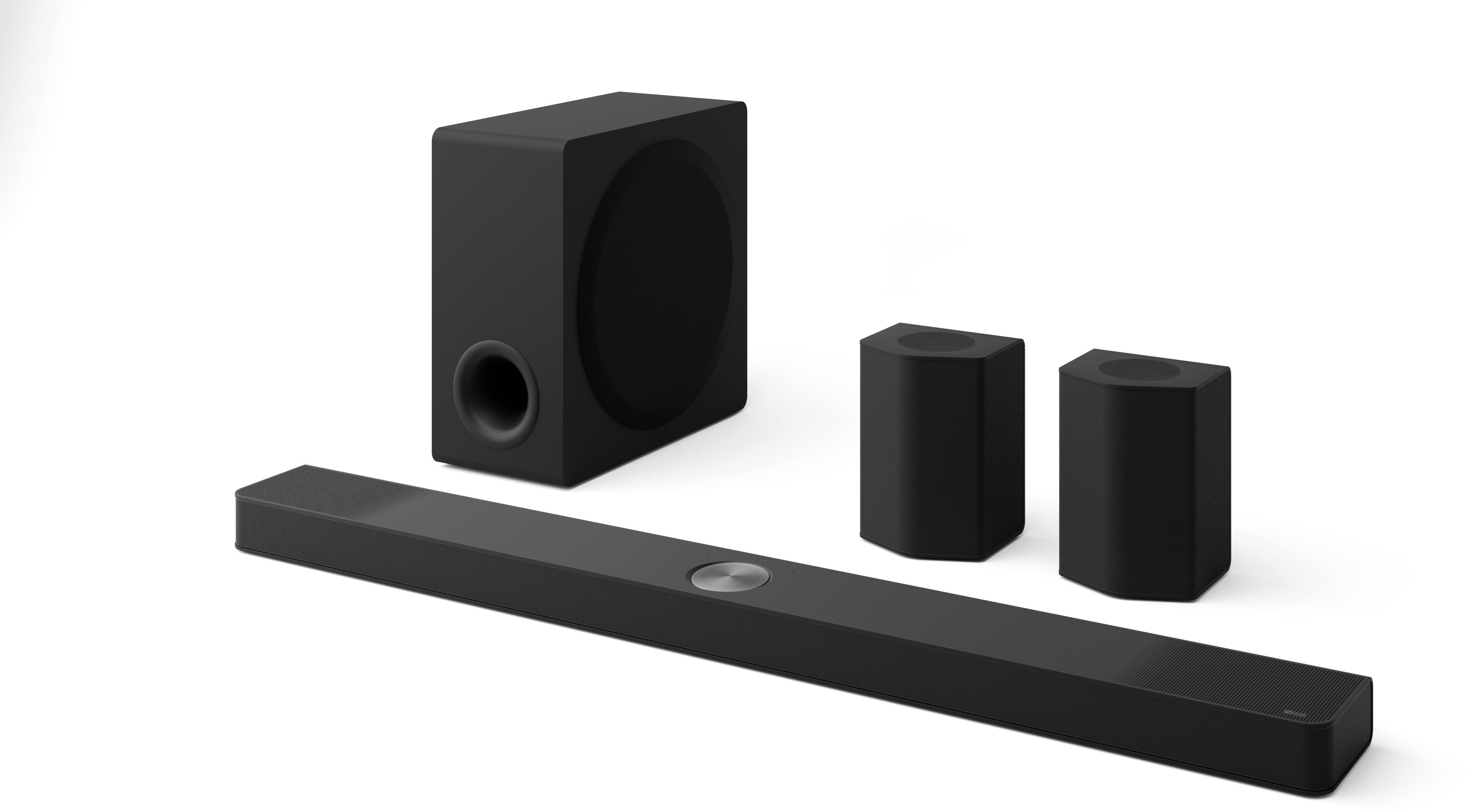 Eine schwarze Soundbar, ein Subwoofer und zwei Lautsprecher sind auf weißem Hintergrund angeordnet. Die Soundbar ist zentriert.