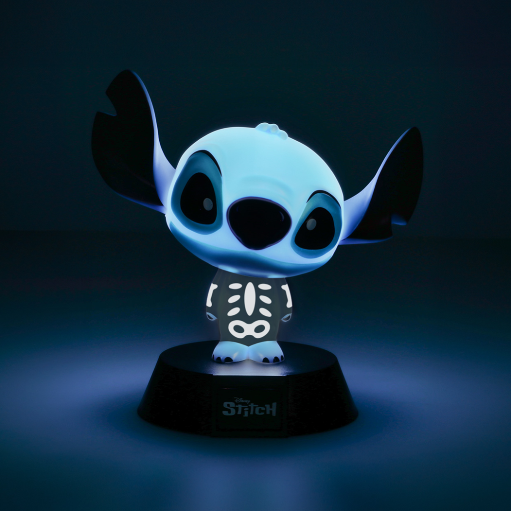 Egy világító Stitch figura csontváz dizájnnal a mellkasán, egy talapzaton áll. Fekete fülek, nagy szemek és kék árnyalat.