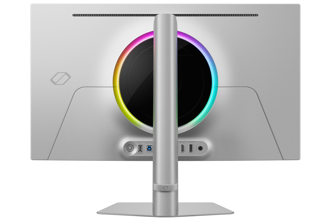 Vista trasera de un monitor de computadora plateado con una luz circular, puertos y soporte. La luz tiene colores del arcoíris.