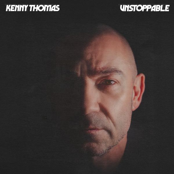 Porträt von Kenny Thomas mit dem Wort 'Unstoppable'. Das Bild ist dunkel, mit Fokus auf sein Gesicht, halb beleuchtet und halb im Schatten.