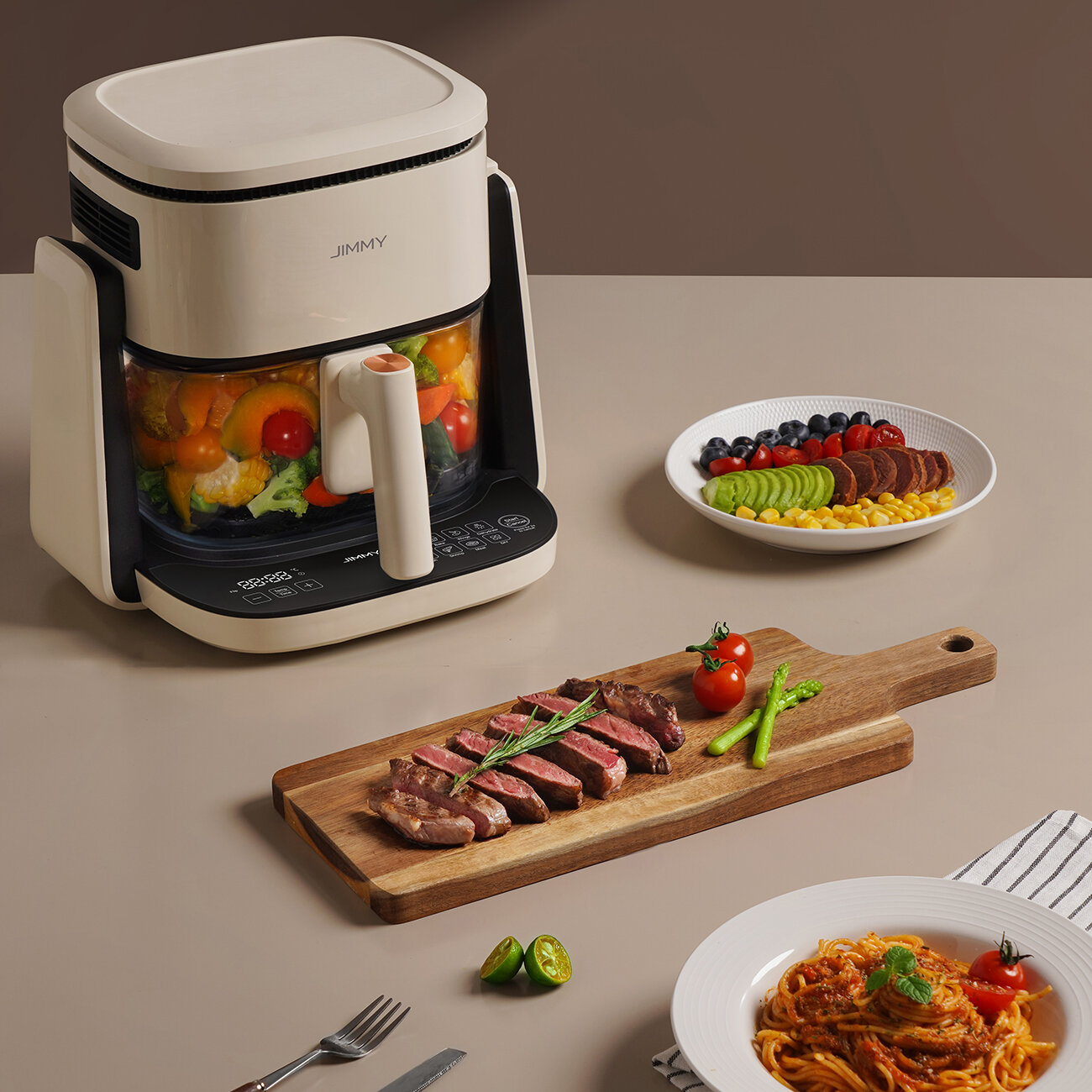 Frytownica powietrzna z warzywami, stek na drewnianej desce, talerz jedzenia i talerz spaghetti.