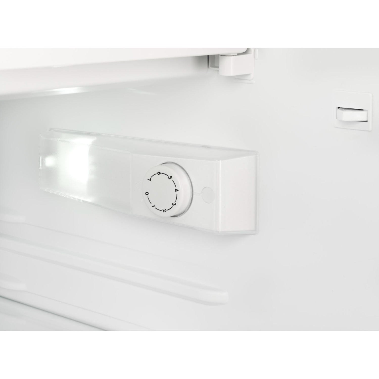 À l'intérieur d'un réfrigérateur, un luminaire blanc avec un cadran de contrôle de la température (0-7) est visible. Un petit interrupteur est à droite.