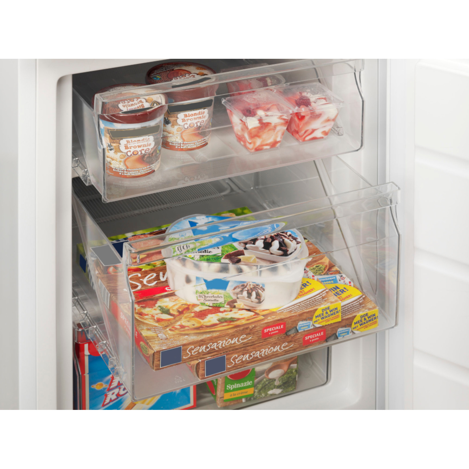 Intérieur d'un congélateur avec divers aliments surgelés : pots de crème glacée, contenants de fruits et boîtes de pizza. Tiroirs en plastique transparent.