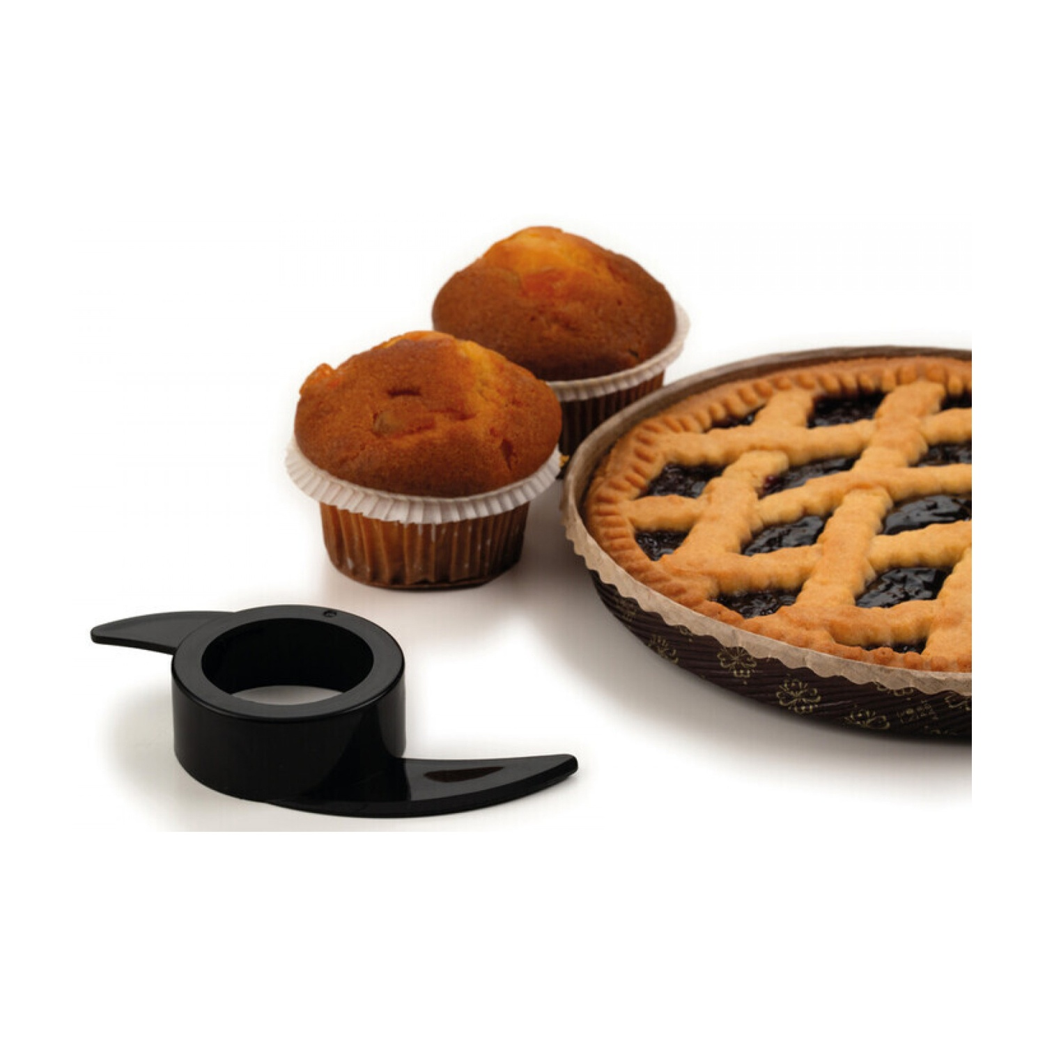 Una lama nera di un robot da cucina è vicino a muffin e una torta a griglia su una superficie bianca.