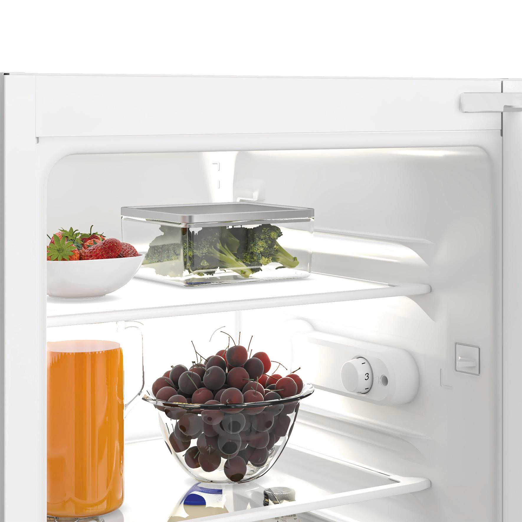 In einem weißen Kühlschrank: Schüssel mit Erdbeeren, Brokkoli, Kirschen und Orangensaft.
