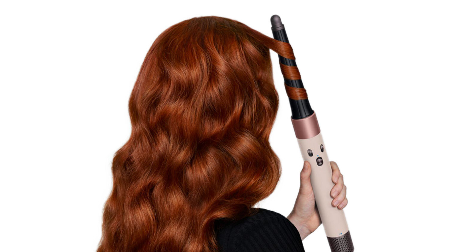 Osoba kręci rude włosy lokówką. Lokówka jest beżowa, czarna i miedziana. Tło jest białe.