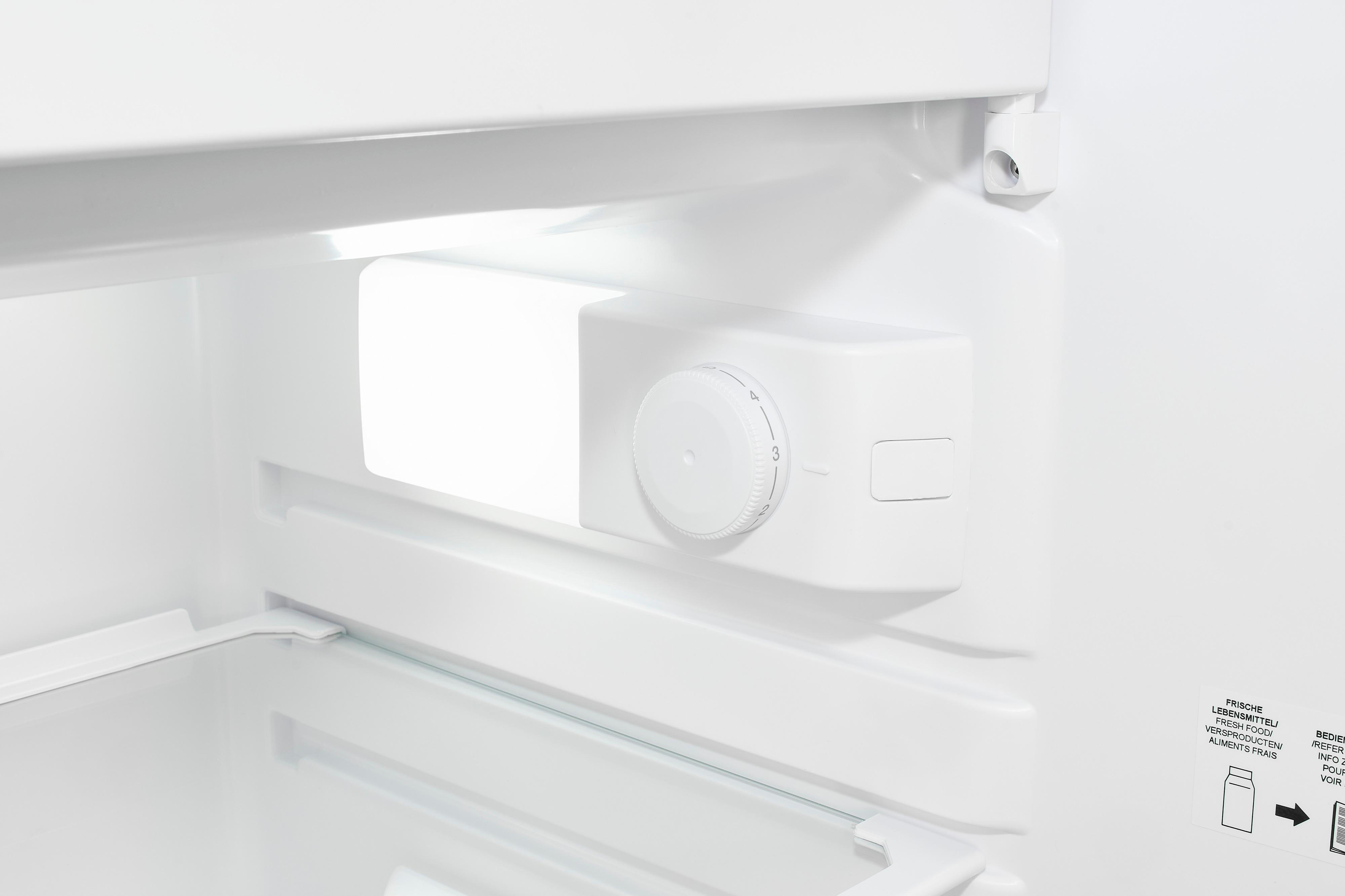 In einem weißen Kühlschrank. Ein weißes Bedienfeld mit Drehknopf ist sichtbar. Die offene Kühlschranktür zeigt ein Glasregal.