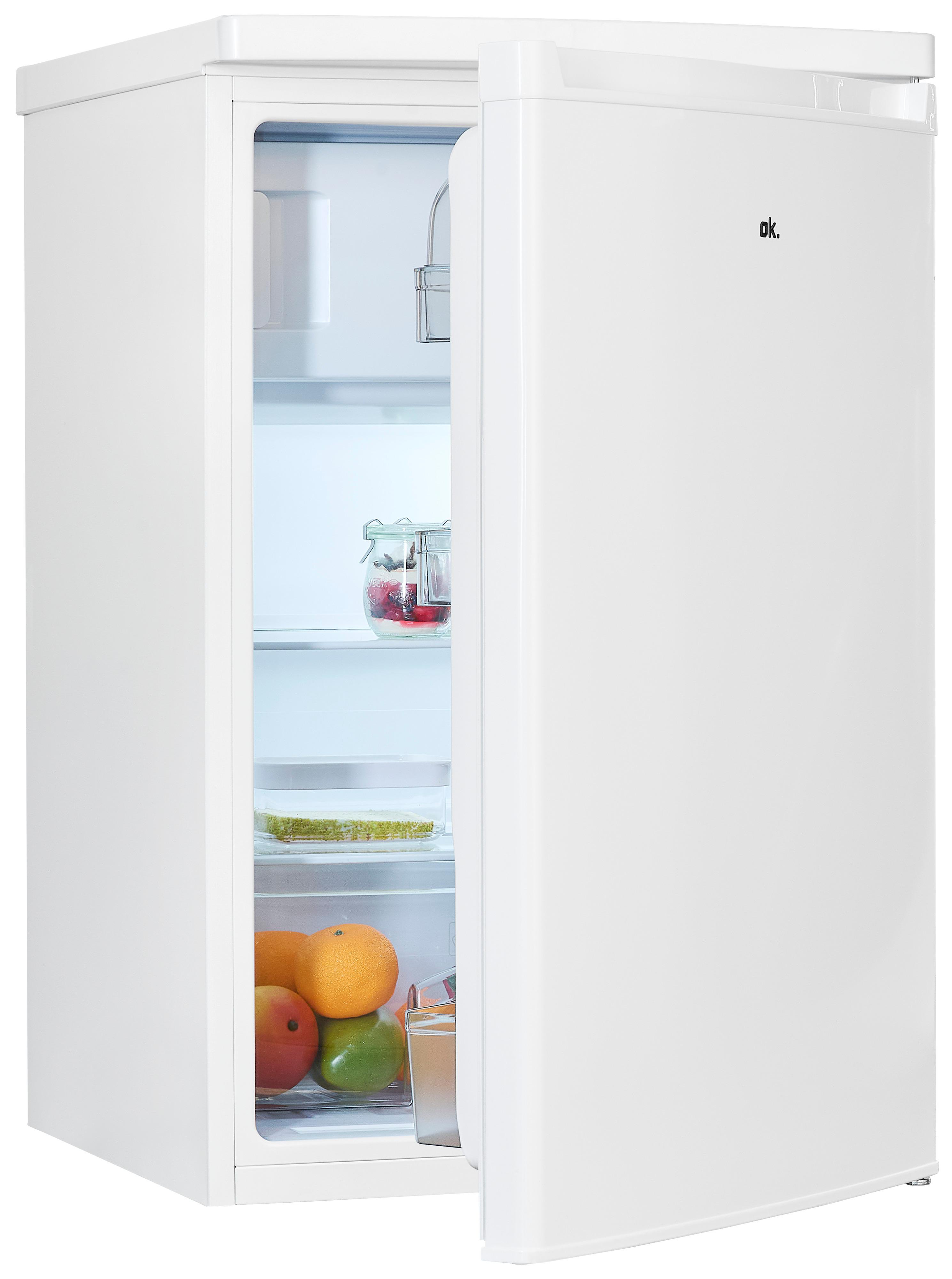 Weißer Mini-Kühlschrank mit geöffneter Tür, der Regale mit Früchten und Gläsern zeigt. Eine rote Mango, Orangen und ein grüner Apfel sind sichtbar.