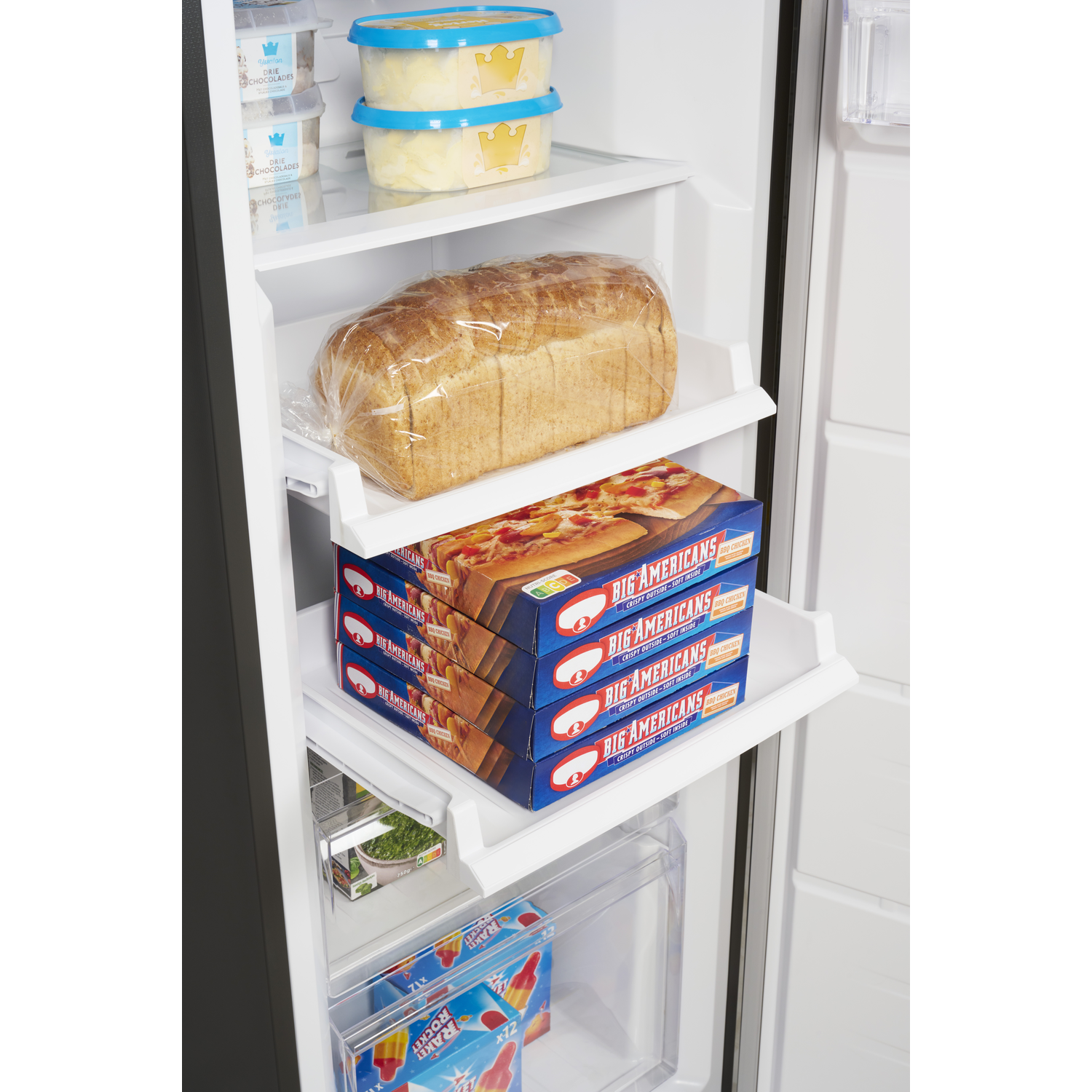 Een open koelkast gevuld met etenswaren zoals brood, pizzadozen, ijs en ijslolly's. Witte planken.