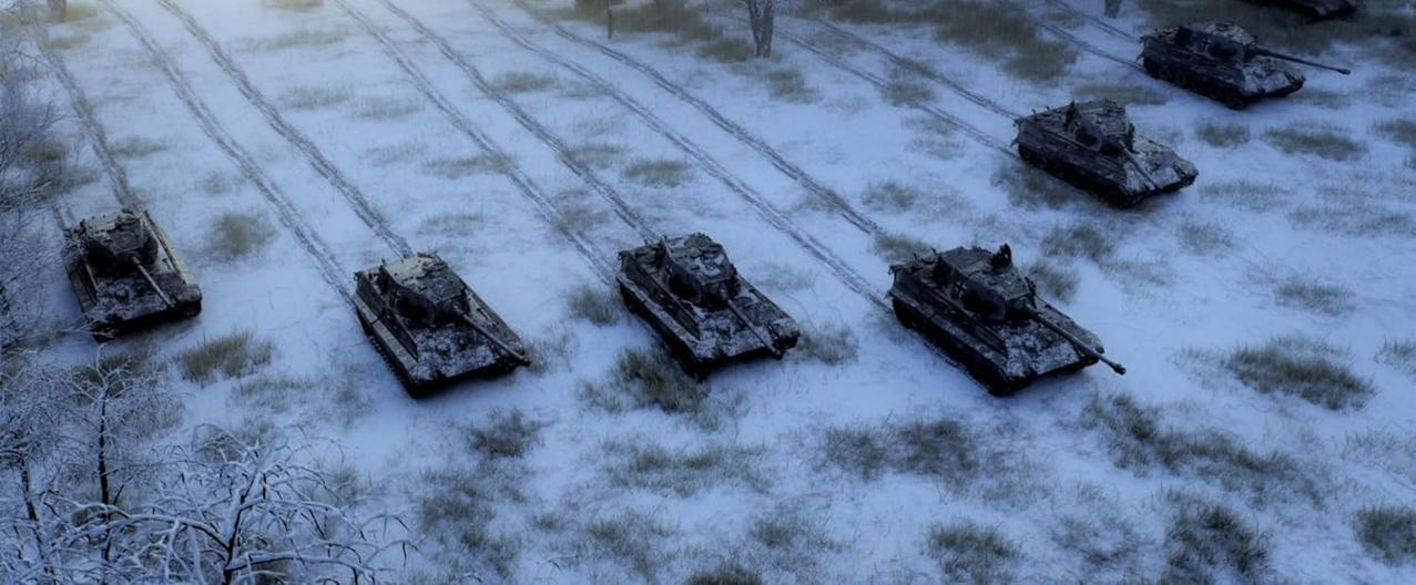 Fünf Panzer bewegen sich über ein schneebedecktes Feld. Kahle Bäume säumen die Ränder. Spuren im Schnee zeigen ihren Weg.