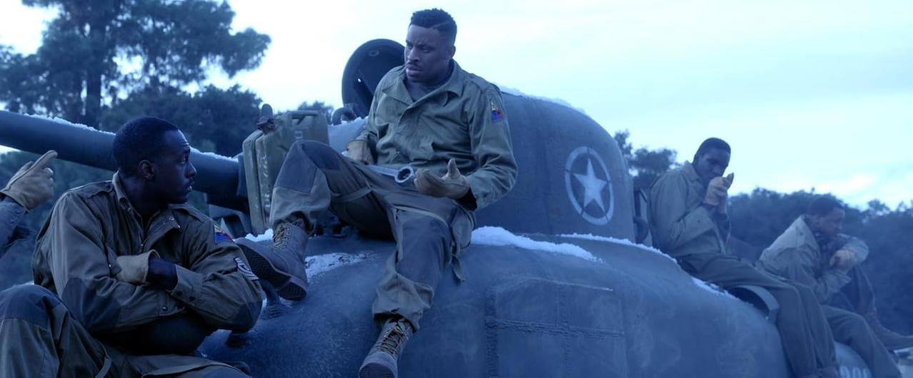 Soldaten sitzen in einer verschneiten Umgebung auf einem Panzer. Ein Mann hält einen Schraubenschlüssel. Andere tragen Uniformen und Handschuhe.
