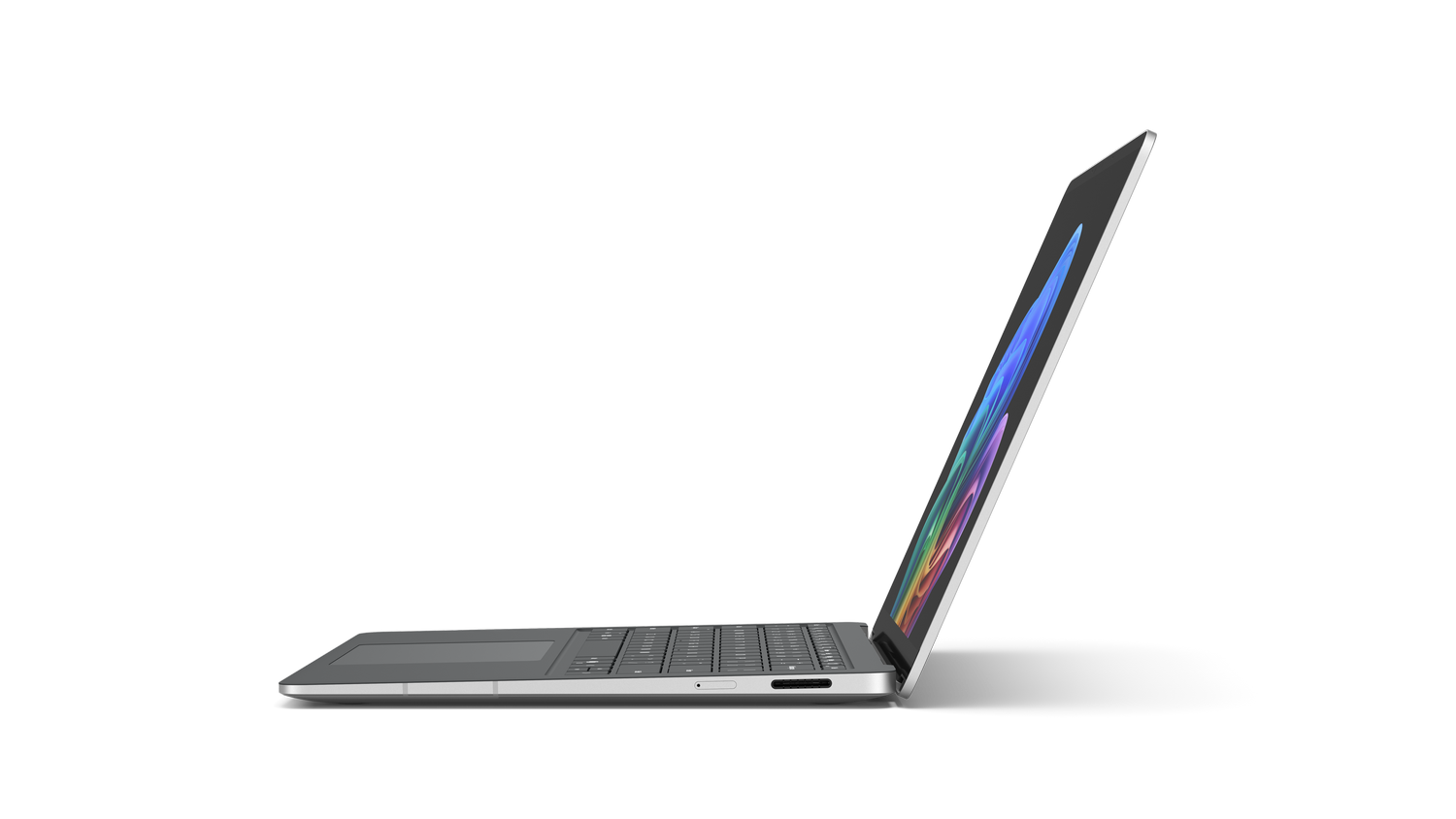 Una laptop plateada está abierta, mostrando una pantalla colorida. Está sobre una superficie gris. Se ve la sombra de la laptop.
