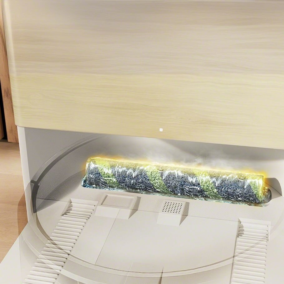 Zbliżenie urządzenia czyszczącego. Ma jasną drewnianą górę i wałek czyszczący z zielonymi i niebieskimi elementami.