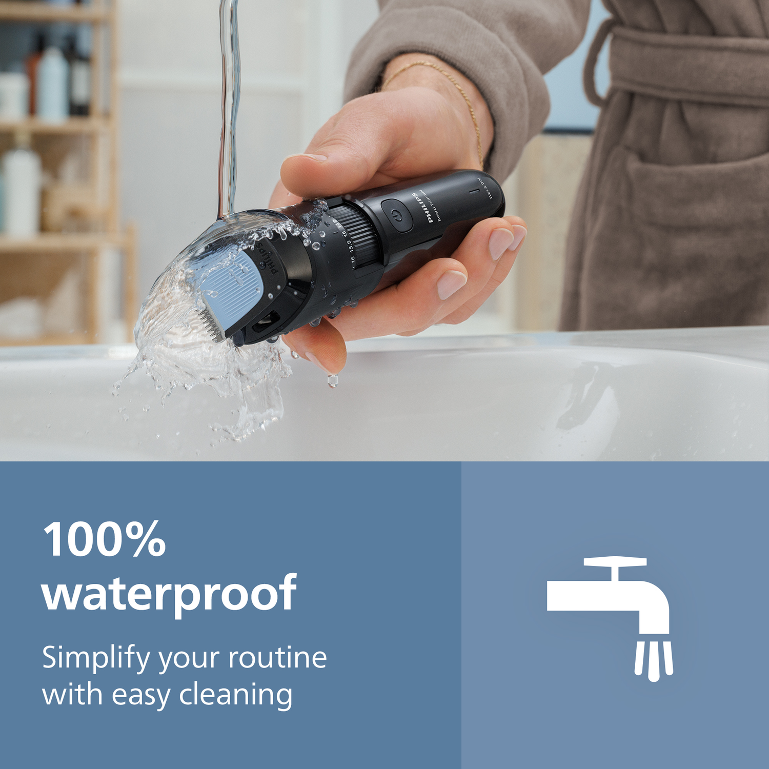 A black Philips beard trimmer being washed with water. A person is holding the trimmer over a white sink. The background is a bathroom.