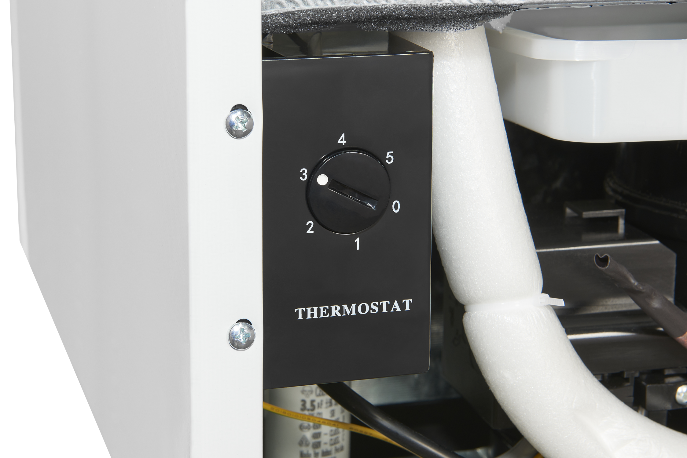 Gros plan sur un cadran de thermostat noir avec les chiffres 0-5. Le cadran est sur un panneau noir avec l'étiquette 'THERMOSTAT'.