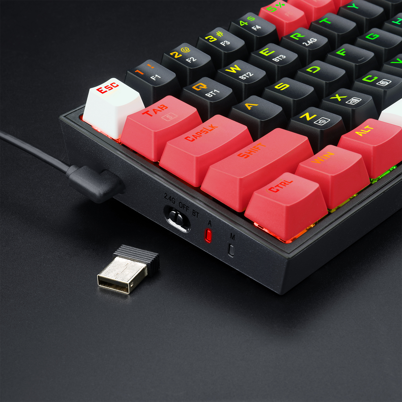 Zbliżenie czarnej klawiatury mechanicznej z czerwonymi i czarnymi klawiszami. Odbiornik USB jest w pobliżu.