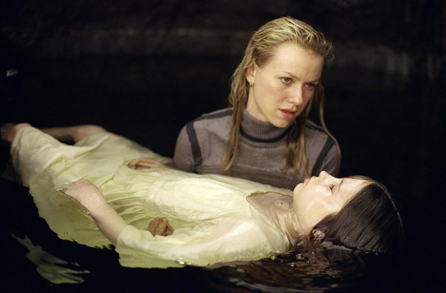 Eine Frau blickt auf ein Mädchen, das im Wasser liegt. Das Mädchen trägt ein gelbes Kleid. Die Frau trägt ein graues Hemd.