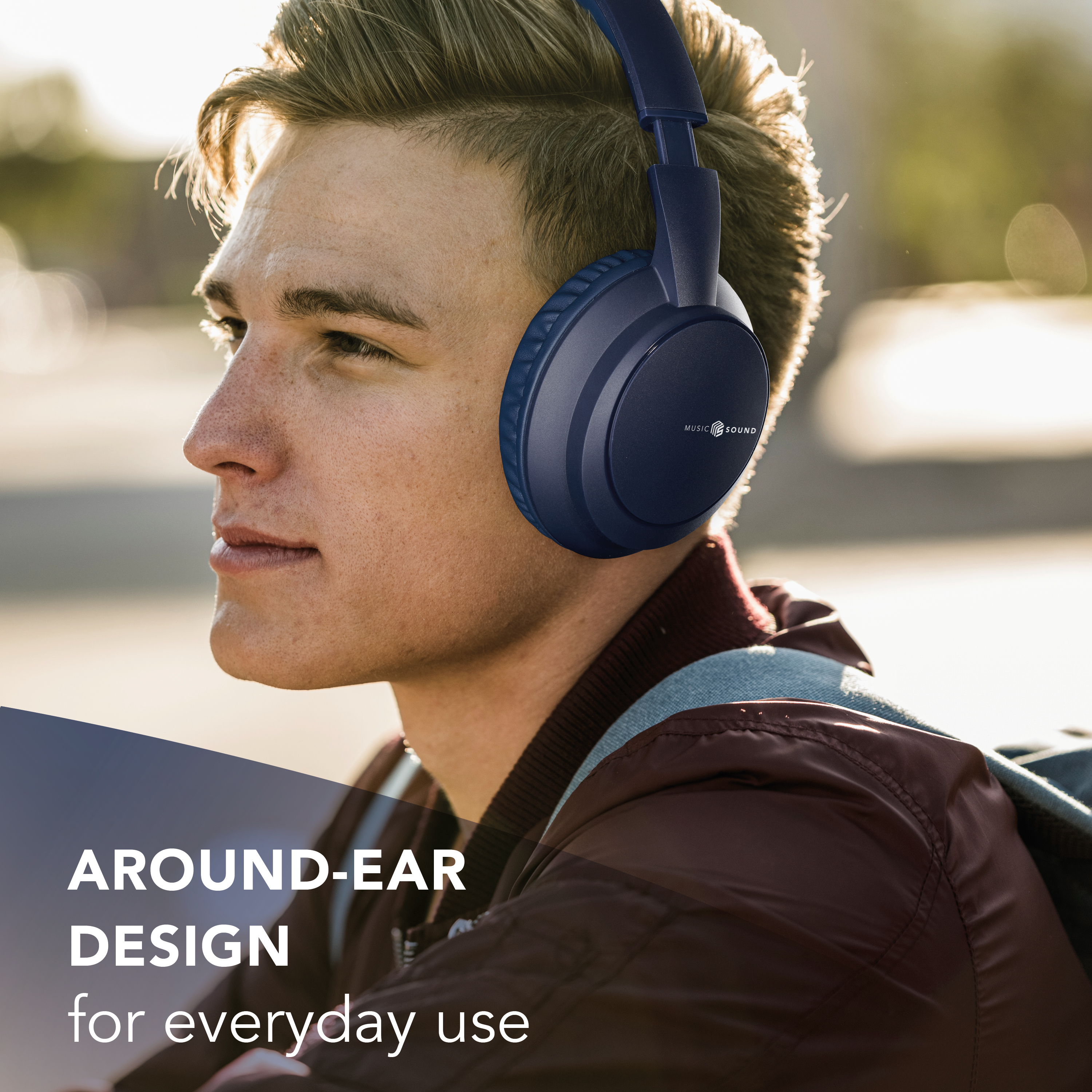 Ein junger Mann trägt marineblaue Kopfhörer. Text: Over-Ear-Design für den täglichen Gebrauch. Er trägt eine burgunderfarbene Jacke.