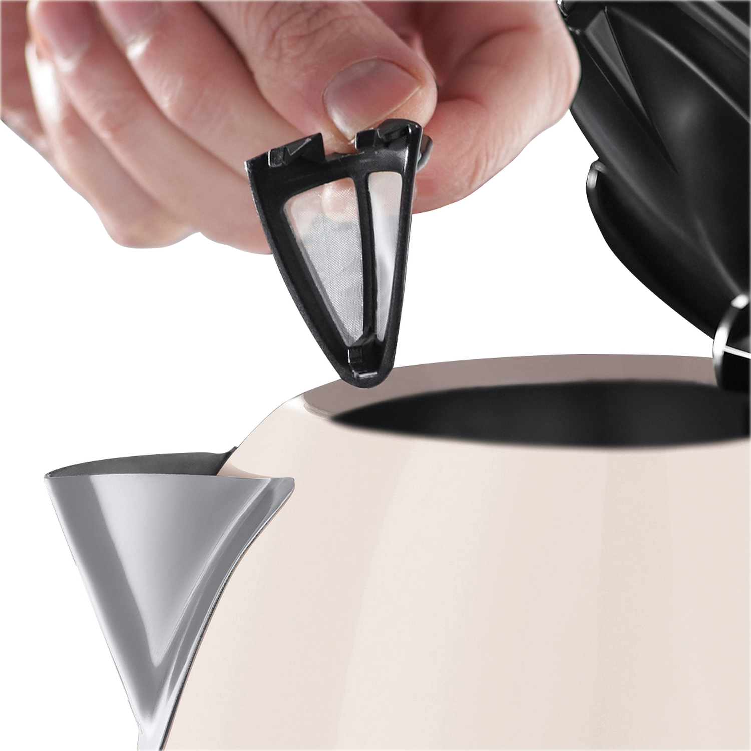 Hand holding a black filter above a beige kettle. The filter is about to be placed into the kettle's opening.