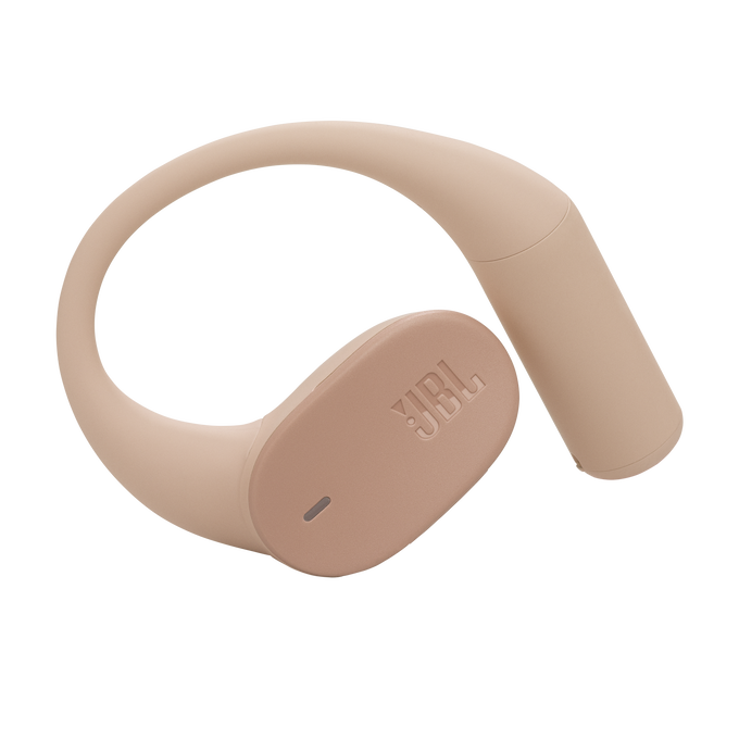 Un auricular JBL de color beige con un diseño curvo. El logotipo de JBL es visible. El fondo es negro.
