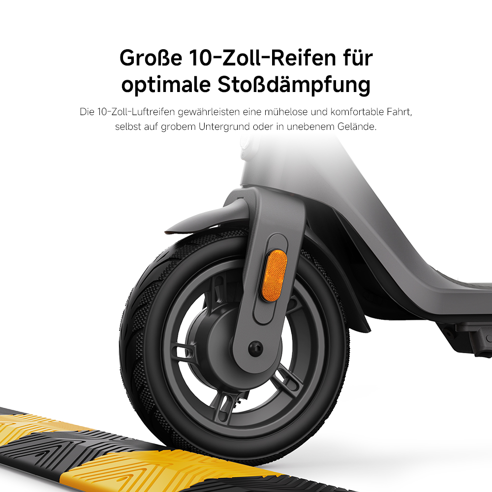 Nahaufnahme eines E-Scooter-Rads mit schwarzem Reifen. Der Roller ist grau. Im Vordergrund befindet sich eine gelb-schwarze Bodenwelle.