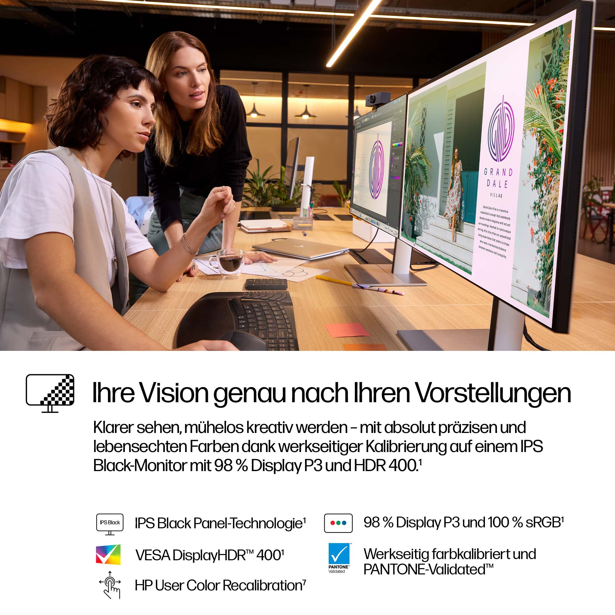 Zwei Frauen betrachten Computerbildschirme mit Design- und Architekturabbildungen auf einem Holztisch. Text über Monitorspezifikationen.