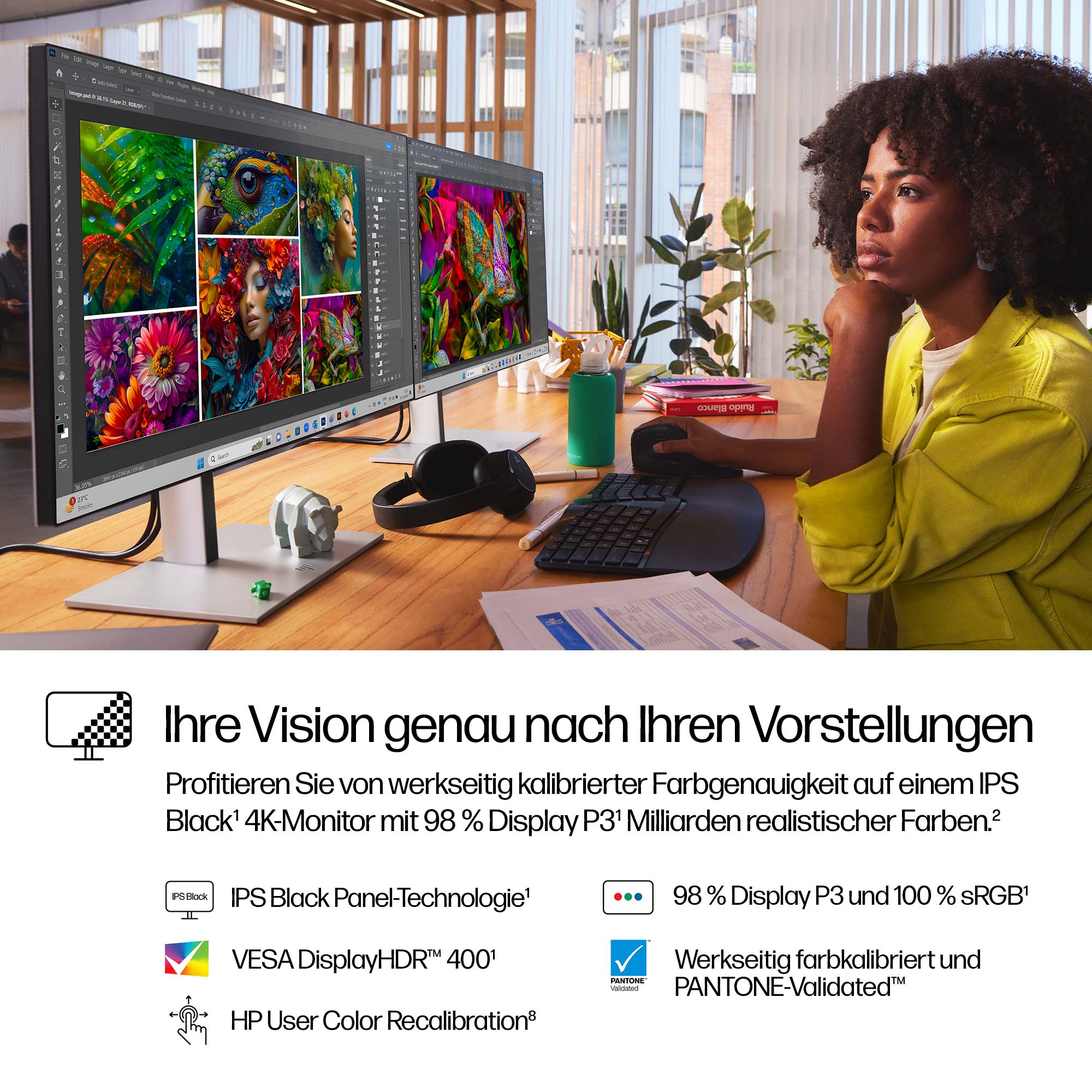 Eine Frau sitzt an einem Schreibtisch mit zwei Monitoren, auf denen farbenfrohe Bilder angezeigt werden. Sie stützt ihr Kinn auf ihre Hand.